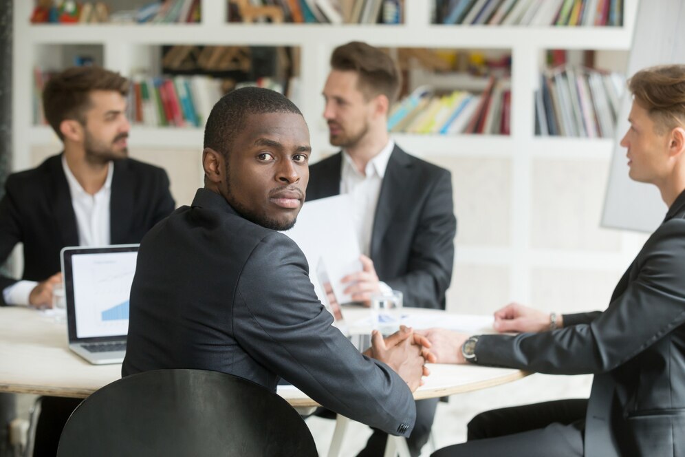 confident-african-american-businessman-looking-camera-sitting-meeting_1163-3922.jpg